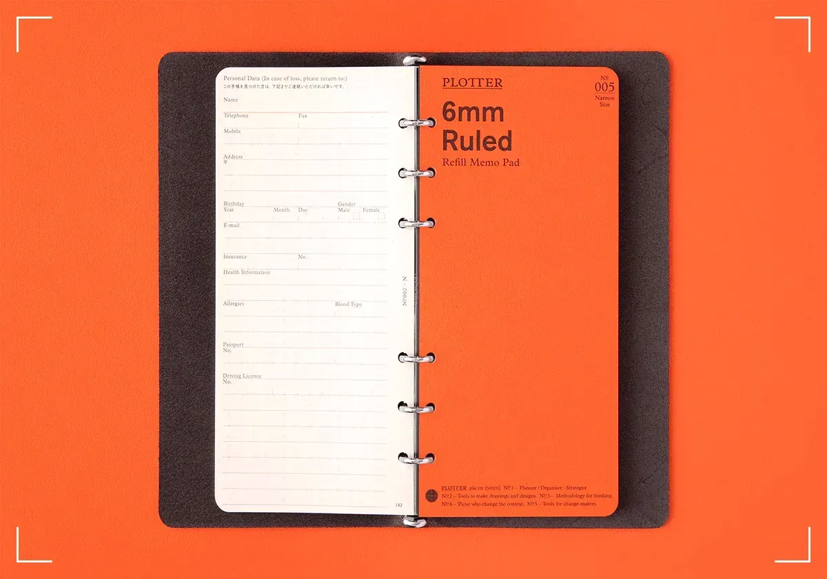 Plotter Narrow notebook lying open on a orange surface.