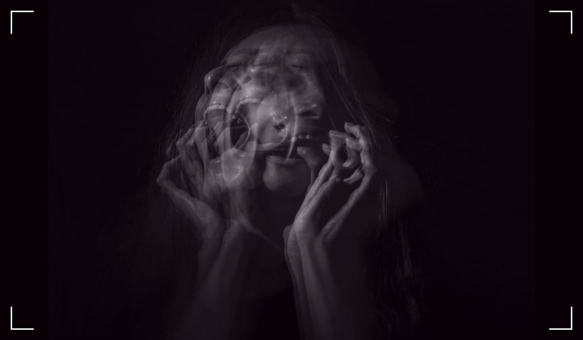 A woman's portrait emerges against a stark black backdrop, where layers of blurred exposures evoke profound suffering.