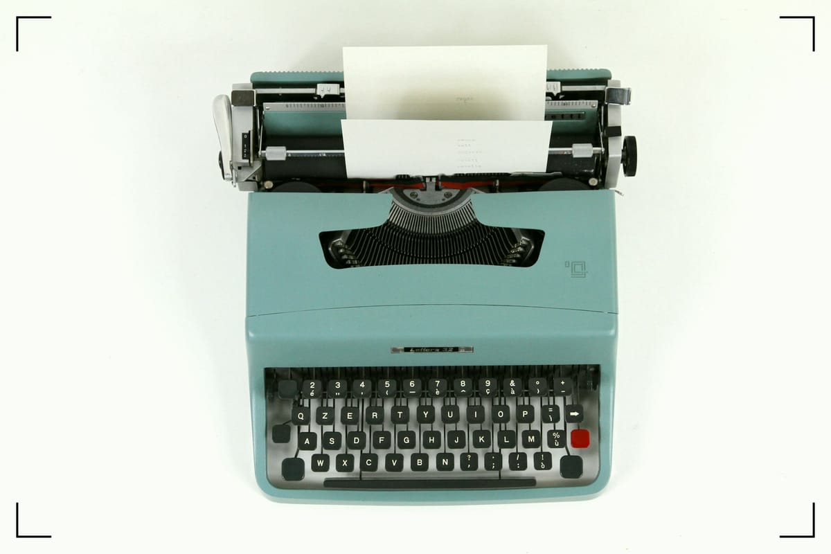 A green typewriter with a blank piece of paper.