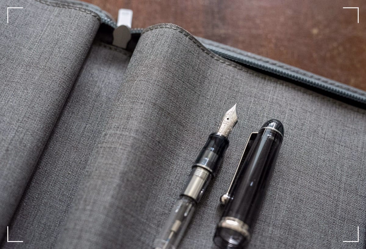 An uncapped fountain pen on a gray cover.