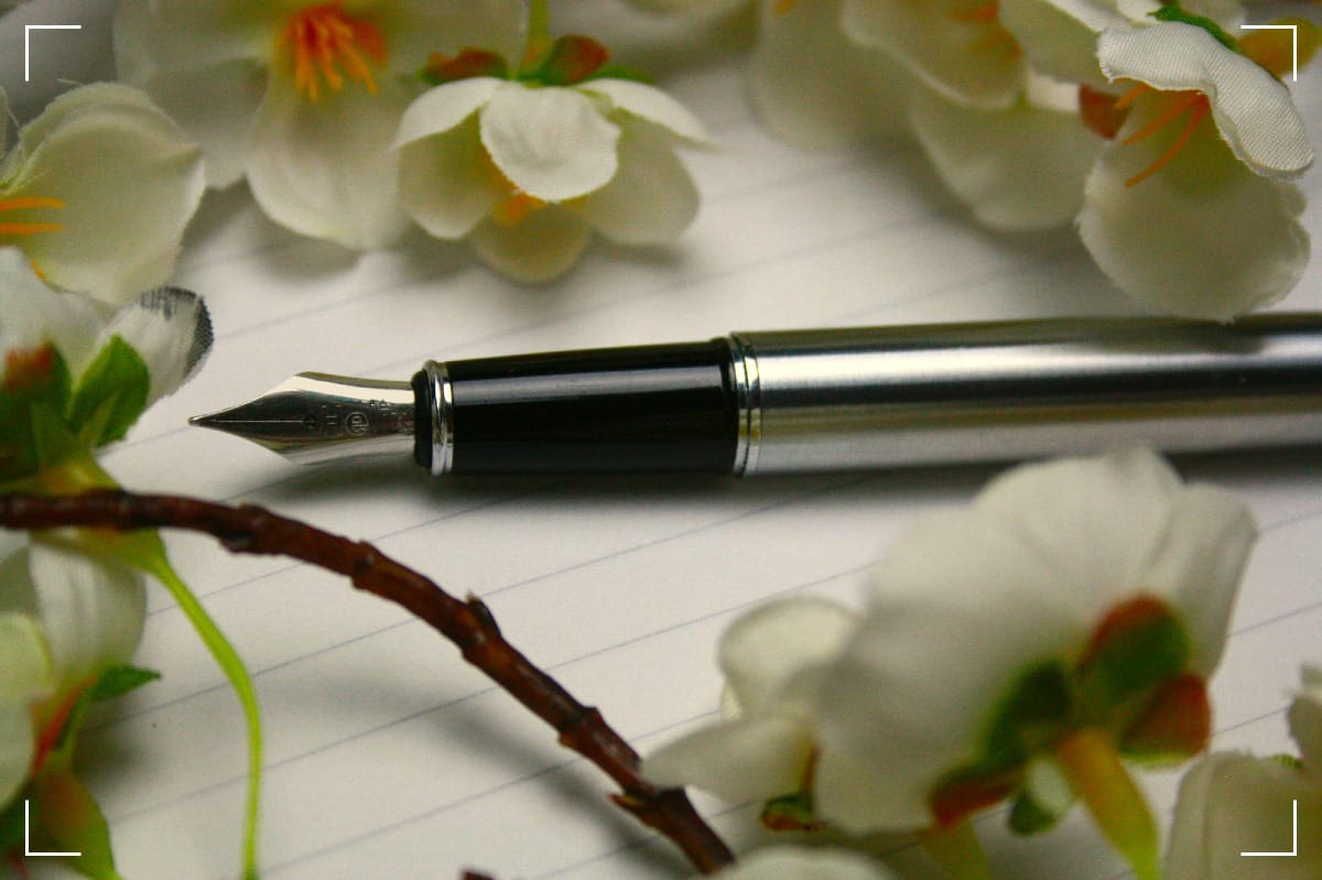 A fountain-pen surrounded with flowers.