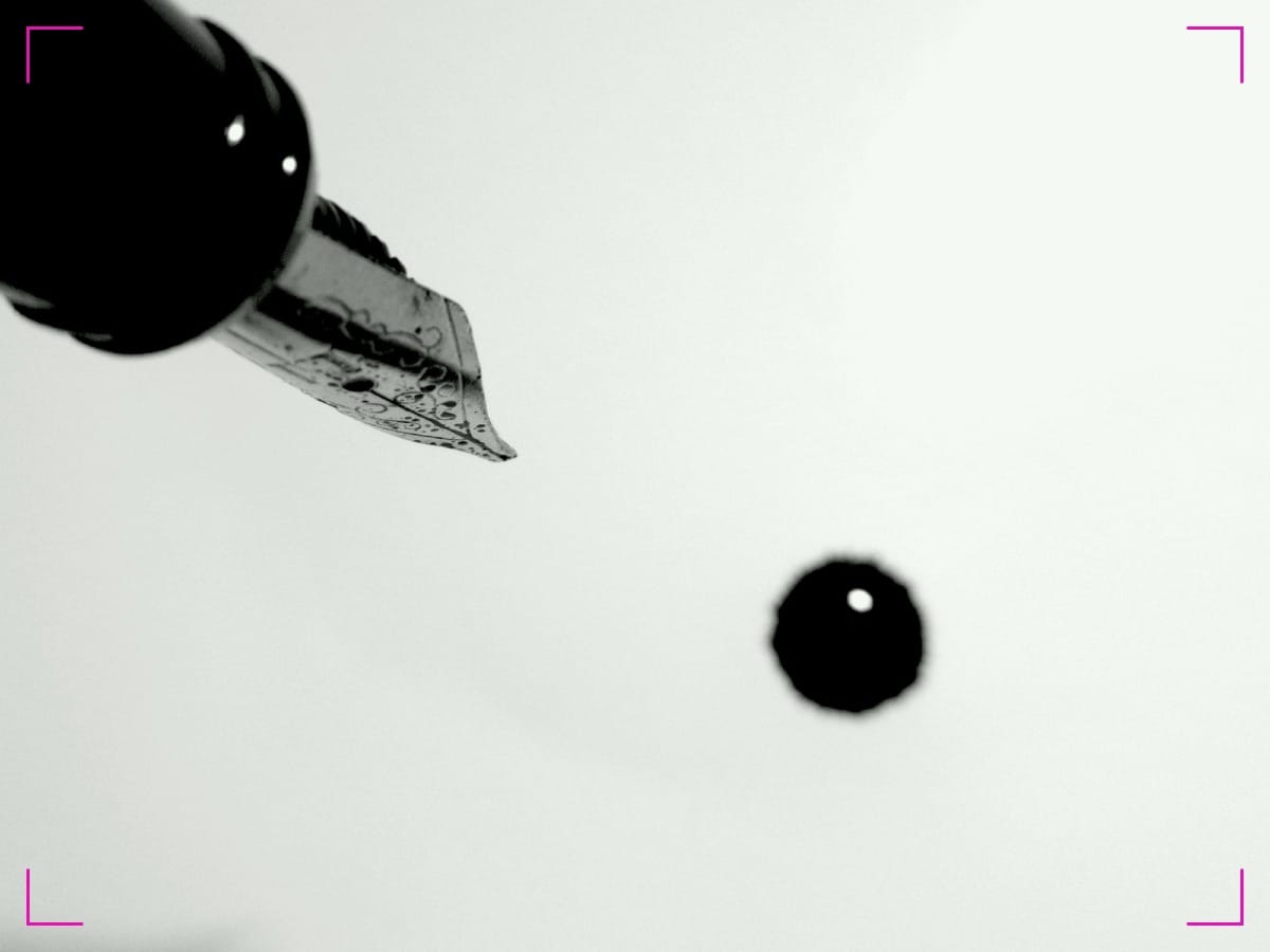 A fountain pen leaking a drop of ink on a paper