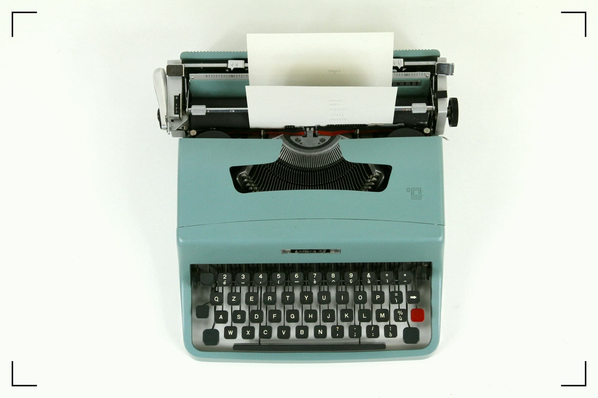 A green typewriter with a blank piece of paper.