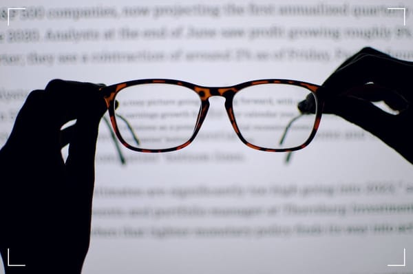 A pair of glasses in front something that looks like a screen withan Internet site. De glasses are sharp and in front while the webpage is behind the glasses and out of focus.